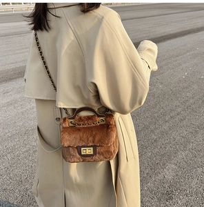 Détail du sac à main en peluche caramel avec finitions cuir et chaîne dorée sur trench