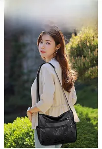 Detail of black embossed floral pattern on textured leather crossbody bag for women