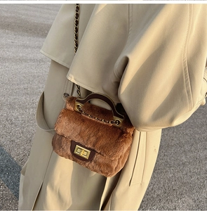 Gros plan d'un sac à bandoulière en peluche marron avec poignée en cuir et fermoir doré chic