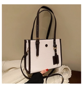 Macro shot of white and brown crocodile pattern tote bag with golden hardware and straps