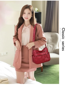 Detailed view of red soft leather shoulder bag with floral embossing and layered zippers