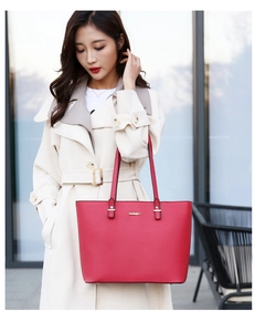 Detail of red faux leather tote bag with gold JINGPIN logo worn with beige coat