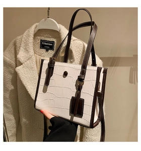 Close-up of white crocodile pattern tote bag with contrast brown trim and gold buckles