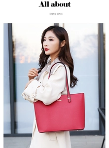 Detail of red Saffiano faux leather tote bag with gold logo on a modern street background