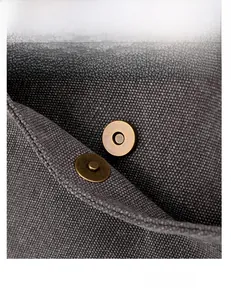 Vista macro della fibbia magnetica in bronzo antico su borsa in tela grigia di qualità