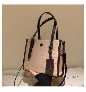 Close-up of beige stone pattern tote bag featuring brown leather handles and metal lock