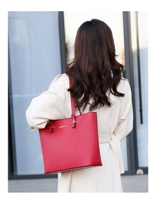 Detail of red faux leather tote bag with gold JINGPIN logo carried by a model