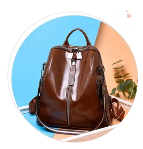 Deep brown oily leather backpack with multi-zipper detail and stylish woven shoulder strap