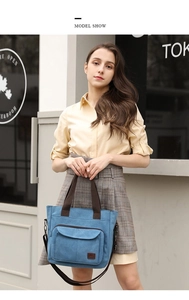 Outdoor street style shot of blue canvas tote bag with adjustable brown strap