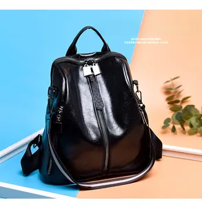 Detailed view of vintage black leather backpack with colorful woven strap and zippers