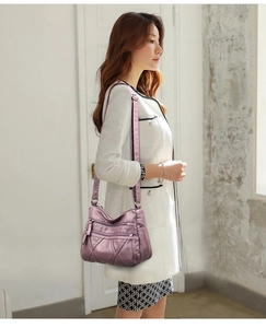 Detail of purple soft PU leather crossbody bag with multiple zipper layers on a model