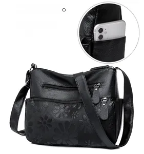 Detail of black embossed floral pattern on leather shoulder bag with multiple zippers