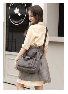 Detail of grey canvas crossbody bag with dark brown handles and premium stitching