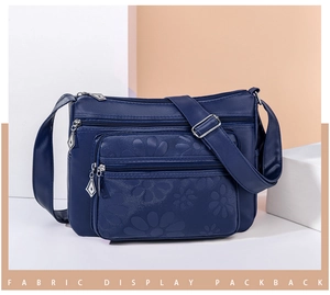 Détail du sac à bandoulière en cuir PU bleu marine avec gaufrage floral et multiples fermetures