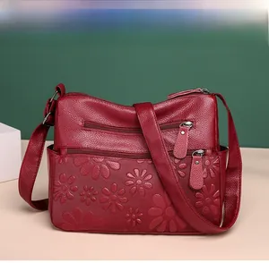 Detail of dark red lychee grain leather crossbody bag with daisy embossed floral design
