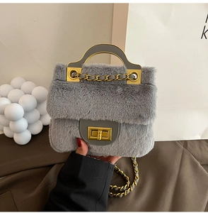 Détail d'un sac à main gris en peluche avec chaîne dorée et fermoir pivotant en métal chic