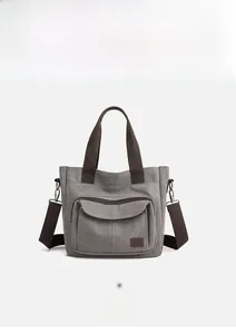 Detailed view of gray canvas tote bag with brown fabric handles and zipper pocket
