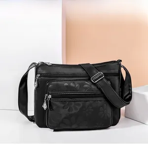 Détail de la texture florale gaufrée et fermetures éclair en métal argenté sur le sac noir