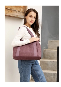 Dettaglio di una borsa tote in tela malva con tasca frontale a scatto e tasche laterali