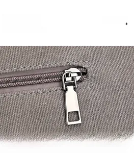 Detailed macro view of smooth silver metal zipper on textured grey-purple canvas fabric