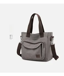 Detail view of large grey canvas tote bag with brown straps and adjustable shoulder strap