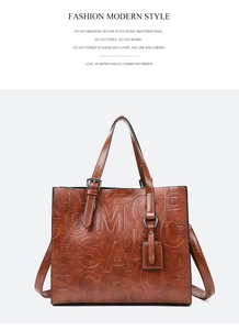 Détail du sac à main en cuir marron avec lettres gaufrées et bandoulière réglable