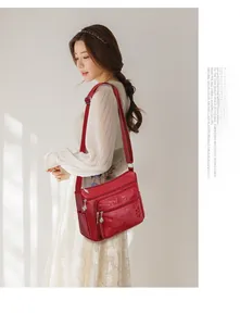 Détail du sac bandoulière rouge en cuir PU avec gaufrage floral et multi-fermetures