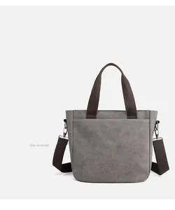 Detail view of large grey canvas bag with brown straps and durable reinforced bottom