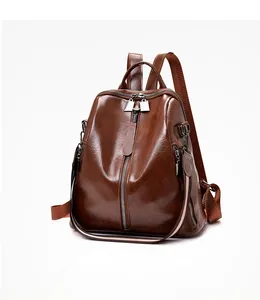 Detail view of smooth dark brown leather backpack with glossy finish and metal zippers
