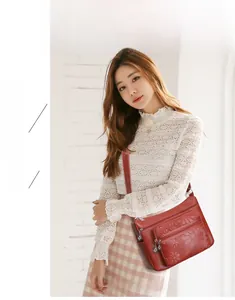 Détail du sac bandoulière en cuir PU rouge avec gaufrage floral et compartiments zippés