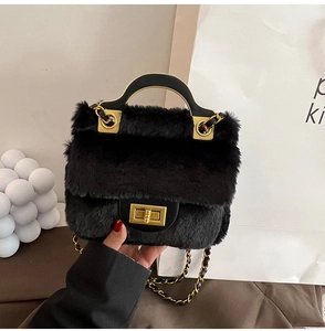 Détails du sac en fausse fourrure noire avec fermoir tournant doré et bandoulière chaîne