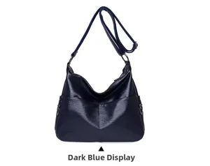 Detail of navy blue crossbody bag showing soft faux leather texture and metallic zippers