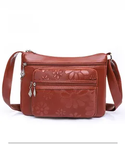 Détail du sac bandoulière en similicuir marron-rouge avec fermetures éclair et motif floral