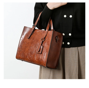 Détail de la texture lettrée embossée sur sac à main en cuir marron avec boucle