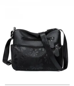 Front view of black pebble leather crossbody bag with floral embossing and zipper pockets