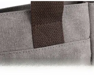 Detail of cross-stitch reinforcement on gray canvas bag with brown handle