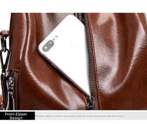 Detailed view of brown leather backpack front zipper pocket holding a smartphone