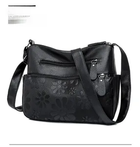 Detailed side view of black leather crossbody bag featuring floral embossed pattern
