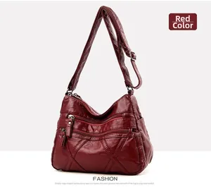 Detail of red faux leather crossbody bag with triple zippers and quilted stitching pattern