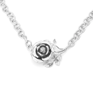 Macro shot of silver rose pendant necklace with detailed petals and link chain