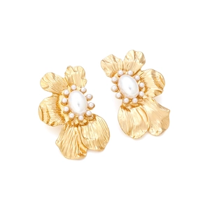 Makroaufnahme matter goldener Blumenohrringe mit einer zentralen ovalen Perlenreihe