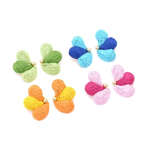 Detailed macro view of handmade raffia butterfly earrings in vibrant gradient colors