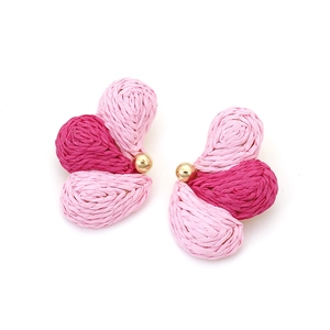 Detail of pink raffia woven flower earring with gradient petals and golden bead center