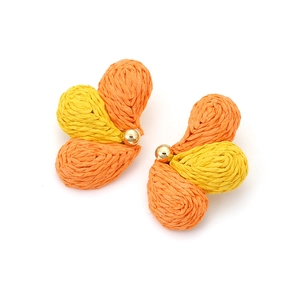 Macro detail of hand-woven raffia butterfly earrings in orange and yellow gradient