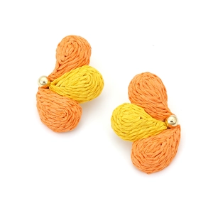 Macro shot of orange and yellow woven raffia flower earrings with a polished gold bead center