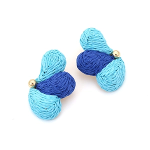 Macro shot of blue gradient raffia woven earrings with central golden bead accent