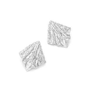 Detailed macro view of silver geometric stud earrings with irregular wrinkled metal texture