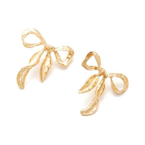 Detailed view of golden bow earrings with textured hammered finish and fringe detail