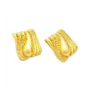Detailed macro view of gold hammered earrings featuring a wavy vintage geometric texture