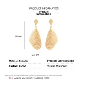 Detail view of large gold-tone wave texture earrings with size 6.4x2.7cm and zinc alloy specs